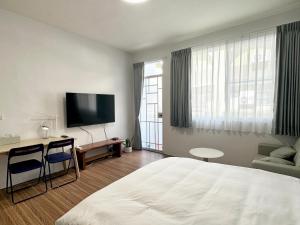 a hotel room with a bed and a desk and a tv at 衛民家 wei min home in Tainan