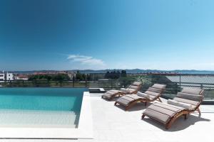 - un ensemble de chaises longues installées à côté de la piscine dans l'établissement Villa Aurum, à Zadar