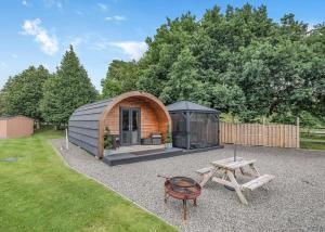 a small greenhouse with a grill and a picnic table at Riverview Holiday Park in Newcastleton