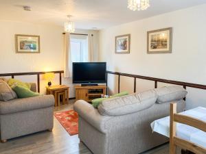 a living room with a couch and a television at The Dairy - Uk44695 in Cheadle