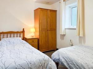 a bedroom with two beds and a cabinet and a window at The Dairy - Uk44695 in Cheadle