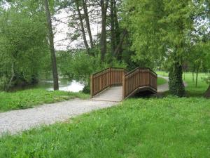 eine Holzbrücke über einen Fluss in einem Park in der Unterkunft Le Domaine de la Cloche in Saint Pavace