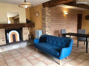 ein blaues Sofa im Wohnzimmer mit Kamin in der Unterkunft Le Domaine de la Cloche in Saint Pavace