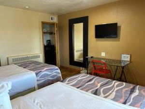 a hotel room with two beds and a table with a television at Valued Stay Mayflower in Madison