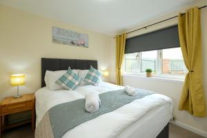 a bedroom with a bed with two stuffed animals on it at Pure Apartments Commuter- Dunfermline South in Fife
