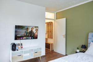a bedroom with a flat screen tv on the wall at Stilvolles Ruhiges Studio - PARKPLATZ, WIFI, TV EM-APARTMENTS DEUTSCHLAND in Bielefeld