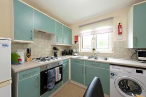 a kitchen with blue cabinets and a washing machine at Pure Apartments Commuter- Dunfermline South in Fife