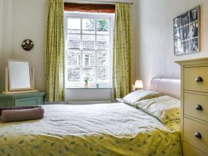 a bedroom with a bed with yellow curtains and a window at The Stables in Sedbergh