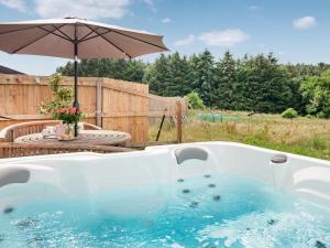 a hot tub with an umbrella in a yard at Old Highwood - Hog End in Luppitt