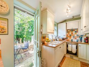 a kitchen with white cabinets and an open door at Maple Cottage in Slingsby
