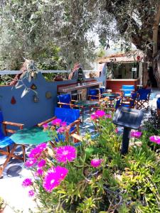 un patio con mesas, sillas y flores púrpuras en Pension Soula, en Skopelos Town