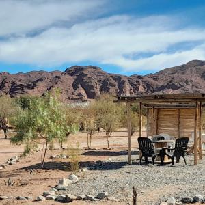 una mesa y sillas bajo un refugio en el desierto en Cabañas Cañones del Triásico en Villa Unión