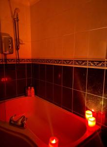 a red bath tub with candles in a bathroom at The Croft Accommodation in Gamrie
