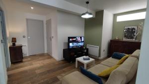 a living room with a couch and a tv at Ruthene Etape Appartement T3 in Rodez