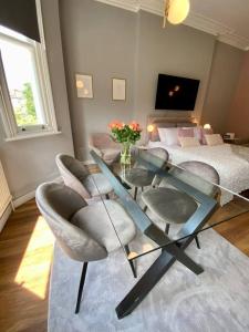Studio for 3 near Regents Park n5 في لندن: غرفة معيشة مع طاولة وكراسي زجاجية وسرير