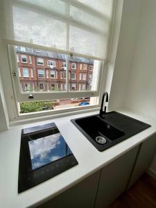 um balcão de cozinha com um lavatório e uma janela em Studio for 3 near Regents Park n5 em Londres
