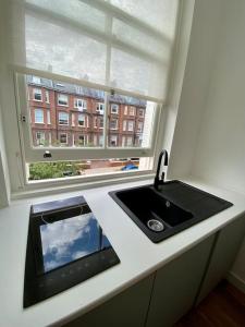 un comptoir de cuisine avec un évier et une fenêtre dans l'établissement Studio for 3 near Regents Park n5, à Londres