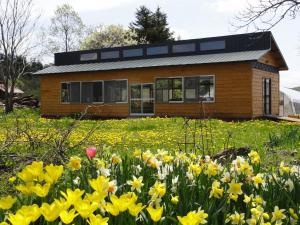 una casa con un campo de flores delante de ella en Guesthouse Yu Yu - Vacation STAY 14848 en Wakkanai