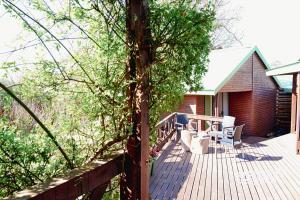 una terraza de madera con mesa y sillas en una casa en Cinnamon & Sage Country Cabins en Dullstroom