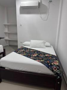 Una cama con una manta floral en una habitación en Hotel Casa Evan en Mompox