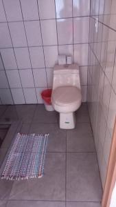 ein Badezimmer mit einem weißen WC und einem roten Korb in der Unterkunft Cabaña el Alto de Berlín in Berlín