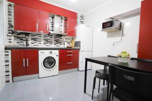 a kitchen with red cabinets and a washing machine at Apartamento Casa Lola in Getxo