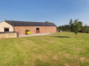 a brick building with a grass field in front of it at Blackberry Barn in Tortworth