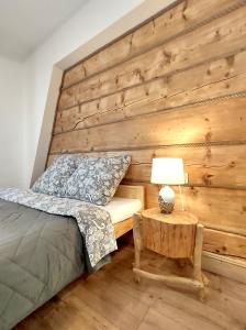 a bedroom with a wooden wall with a bed and a lamp at Apartamenty Przy Rynku Szaflary in Szaflary