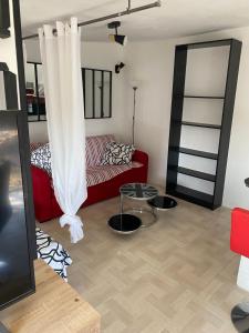 een woonkamer met een rode bank en een tafel bij Studio jardinet Couloumines in Rivesaltes