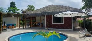 a small house with a pool and an umbrella at Cabaña de Elsa in Olón