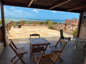 a patio with a table and chairs and the ocean at Casa da Vovó in Jericoacoara
