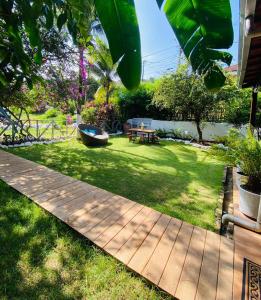 a garden with a wooden walkway and a table and a bench at Estrela Praia in Fernando de Noronha