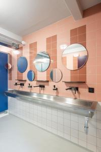 a tiled bathroom with mirrors and a sink at Hostel het Archief in Zwolle