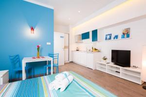 Split Dreams Apartments في سبليت: غرفة زرقاء وبيضاء مع سرير ومطبخ