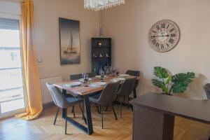 uma sala de jantar com uma mesa e um relógio na parede em Urban Oasis, Stylish Short Stay Apartment in Piraeus Center em Pireu