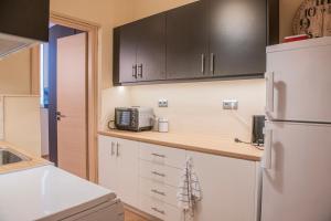 une cuisine avec des armoires blanches et un réfrigérateur blanc dans l'établissement Urban Oasis, Stylish Short Stay Apartment in Piraeus Center, au Pirée