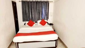 Habitación pequeña con cama con almohadas rojas en OYO Flagship Hotel Capital, en Rajkot