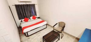 a bedroom with a bed with red pillows and a chair at OYO Flagship Hotel Capital in Rajkot