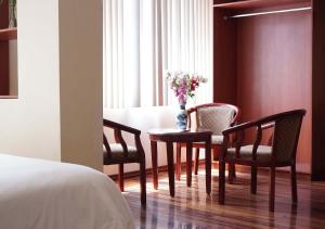 una habitación con una mesa con sillas y un jarrón de flores en Hotel Lottus, en Quito