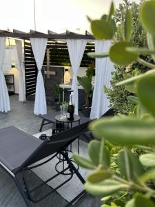 a hammock on a patio with white curtains and plants at Terrazza Poesìa in Brindisi