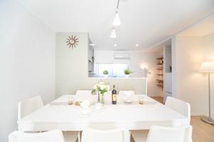 una sala da pranzo bianca con tavolo bianco e sedie bianche di ナガシマリバーサイドリゾート - Vacation STAY 94113v a Kuwana
