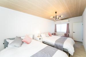 twee bedden in een kamer met wit en roze bij ナガシマリバーサイドリゾート - Vacation STAY 94113v in Kuwana