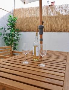 Una botella de vino y dos copas en una mesa de madera. en Caparica Coast Townhouse Apartments en Charneca