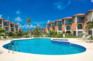 a swimming pool in front of some apartments at Beach Living at Villas Pappagallo Beachfront 22 in West Bay