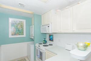 a kitchen with blue walls and white cabinets at Beach Living at Villas Pappagallo Beachfront 22 in West Bay +10 photos