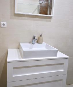Caparica Coast Townhouse Apartments في تشارنكه: حمام مع حوض أبيض ومرآة