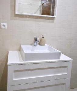 a bathroom with a white sink and a mirror at Caparica Coast Townhouse Apartments in Charneca +12 photos