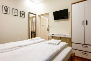 a bedroom with two white beds and a tv at ApartPro Apartments, Veliko Tarnovo in Veliko Tŭrnovo