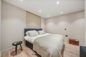 1 dormitorio con 1 cama grande con sábanas blancas en Reside Global - 2 Bed Flat Walking Distance From Harrods, en Londres