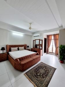 a bedroom with a large bed and a rug at Three Bed Attached Bath Netflix Wifi Smart TV Parking WFH Desk Near Airport in Islamabad